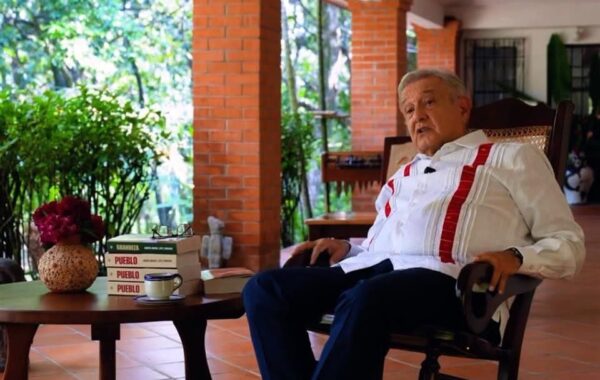 El expresidente López Obrador sentado a un lado de ejemplares del libro Pueblo