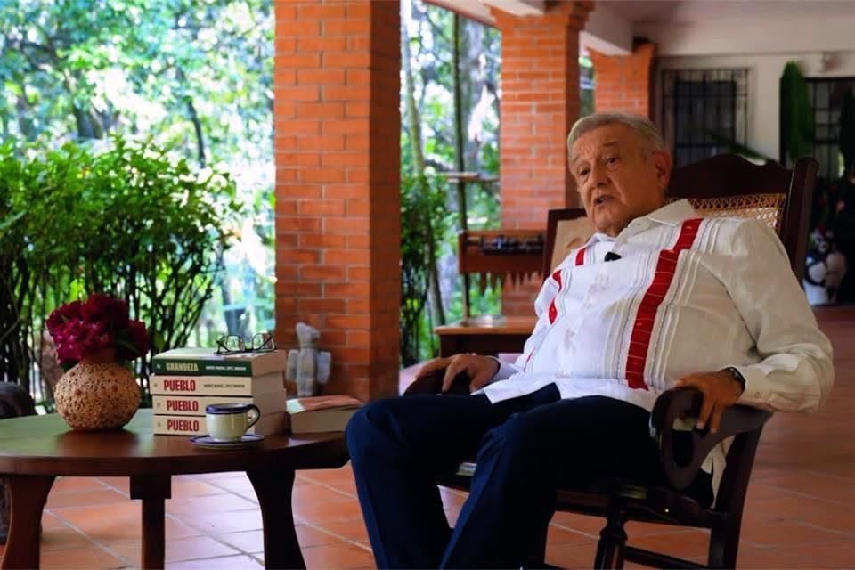 El expresidente López Obrador sentado a un lado de ejemplares del libro Pueblo